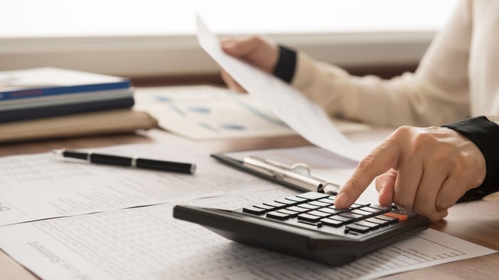 Hands using a calculator over invoices